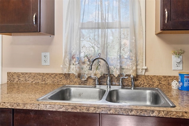 interior details with a sink and dark brown cabinetry