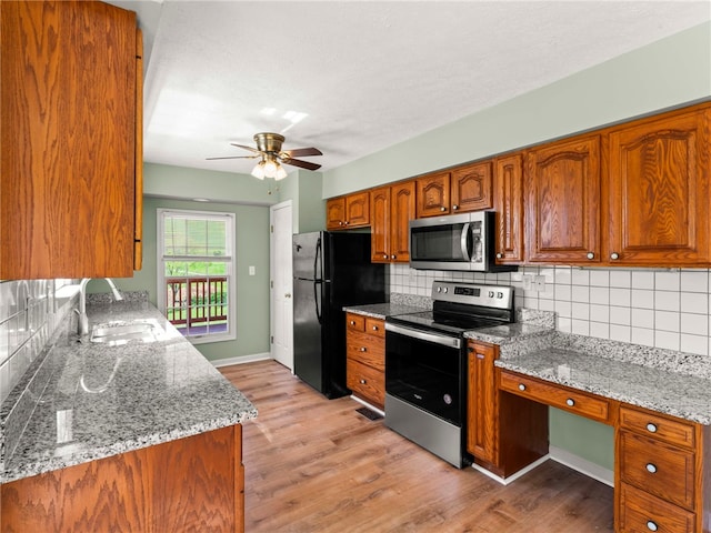297 Rainey Rd, Somerset Twp, PA 15330 - kitchen featuring appliances with stainless steel finishes, tasteful backsplash, brown cabinets, a sink, and light wood finished floors