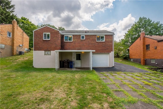 back of house with an attached garage, a yard, driveway, and brick siding