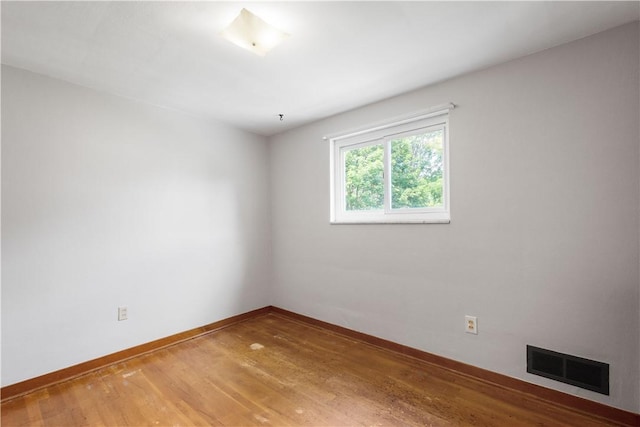 empty room with baseboards, visible vents, and light wood-type flooring