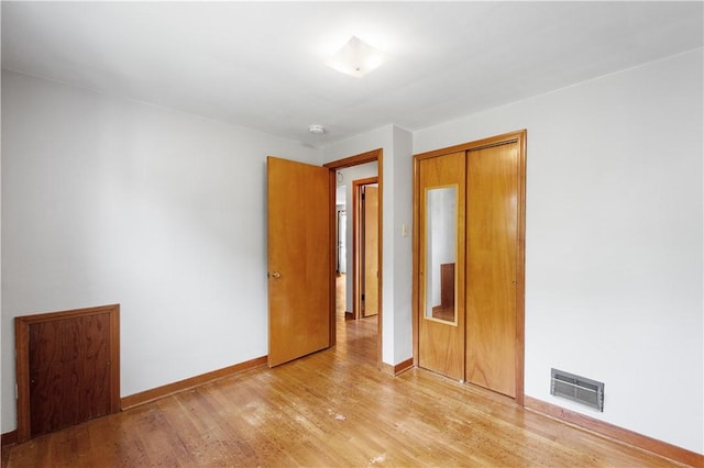 unfurnished bedroom with baseboards, a closet, light wood finished floors, and visible vents