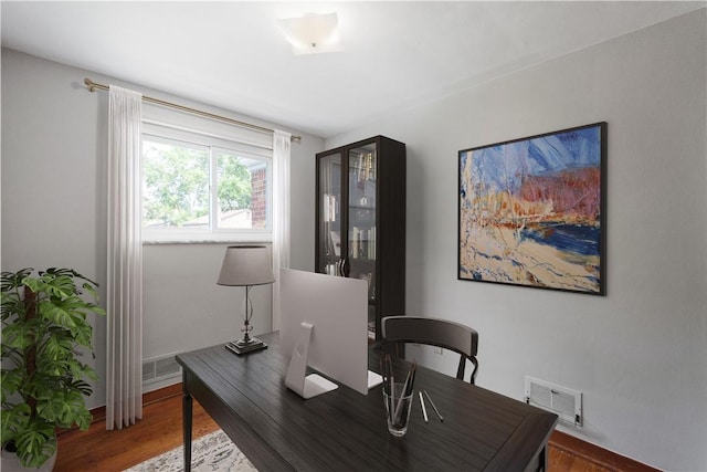 home office featuring baseboards, visible vents, and wood finished floors
