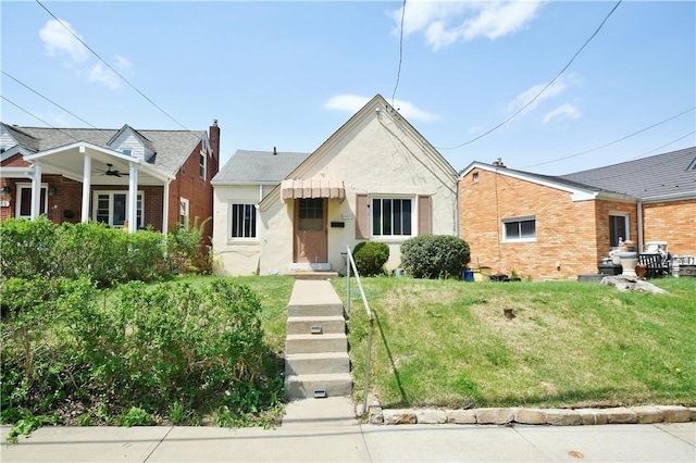 view of front facade featuring a ceiling fan, a front yard, and stucco siding