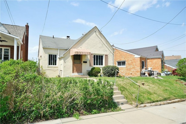 view of front of house featuring brick siding, a front lawn, and stucco siding