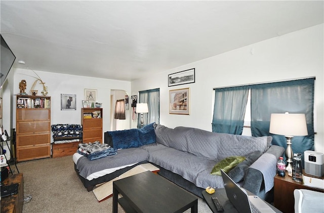 carpeted living room featuring arched walkways