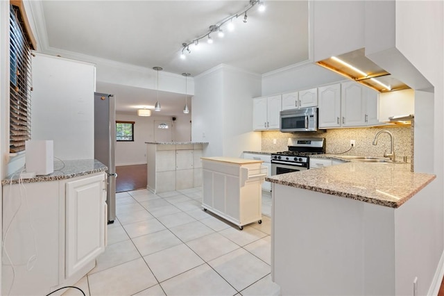 kitchen with a sink, a peninsula, decorative backsplash, white cabinets, and appliances with stainless steel finishes