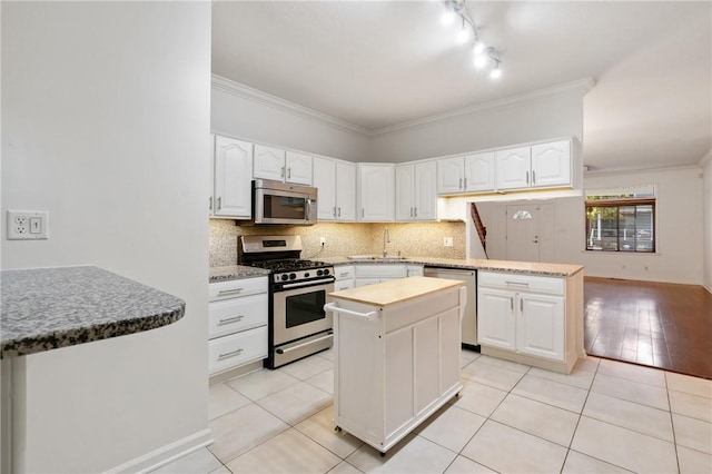 kitchen with a sink, stainless steel appliances, a kitchen island, and white cabinets