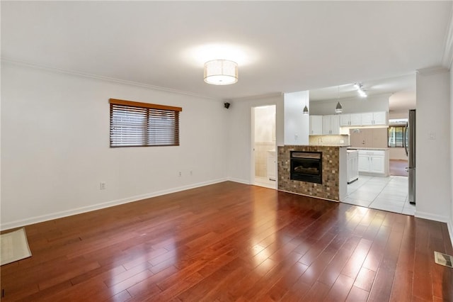 unfurnished living room with light wood finished floors, baseboards, and ornamental molding