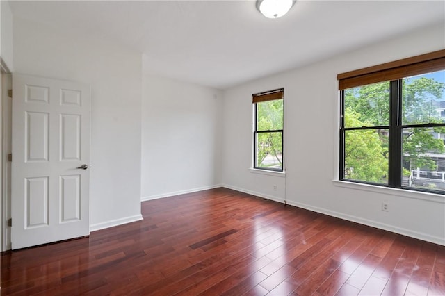 empty room featuring dark wood-style flooring and baseboards