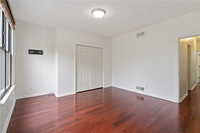 unfurnished bedroom with baseboards, dark wood-style floors, and visible vents