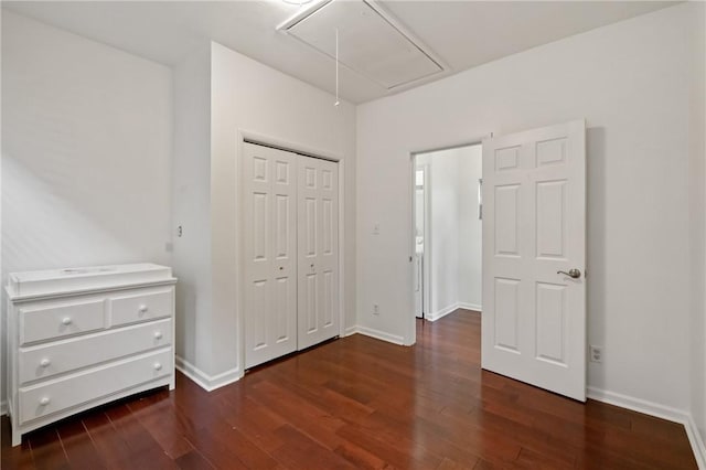 unfurnished bedroom with baseboards, attic access, and wood finished floors