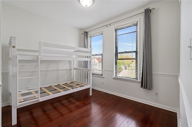 unfurnished bedroom with hardwood / wood-style flooring and baseboards