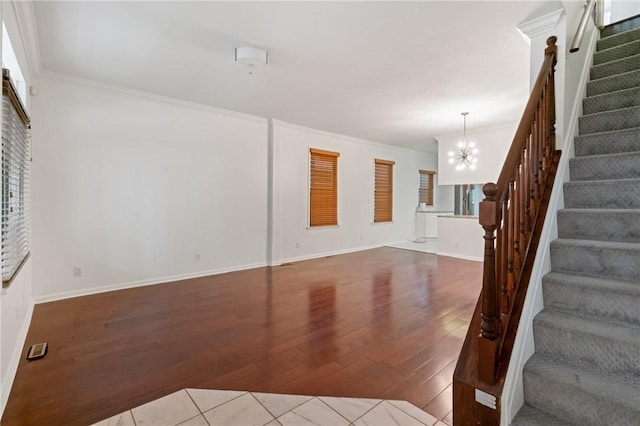 unfurnished living room with ornamental molding, stairway, a chandelier, and wood finished floors