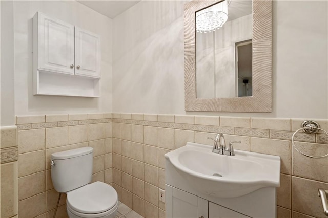 half bathroom with a wainscoted wall, tile walls, and toilet