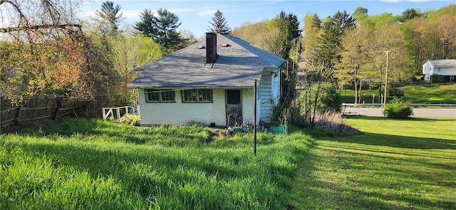 back of property with a lawn, a chimney, fence, and brick siding