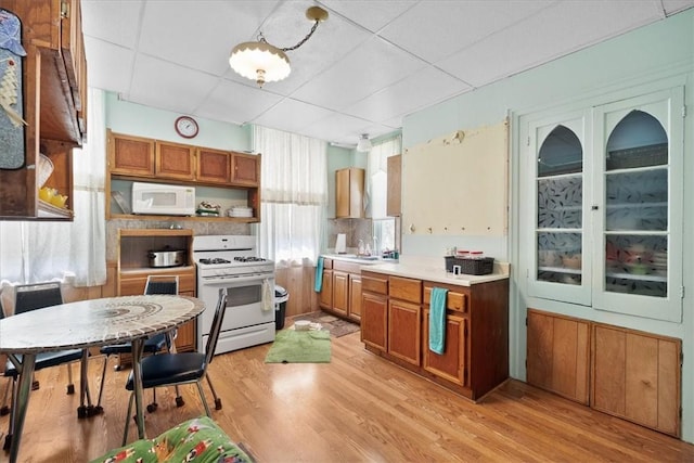 101 Clara St, Millvale, PA 15209 - kitchen featuring white appliances, brown cabinets, a drop ceiling, and light wood finished floors