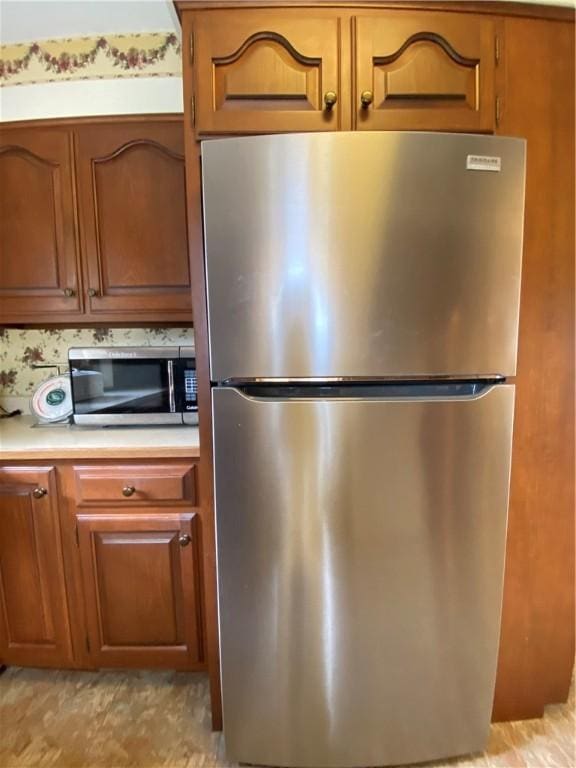 kitchen featuring brown cabinets, appliances with stainless steel finishes, and light countertops