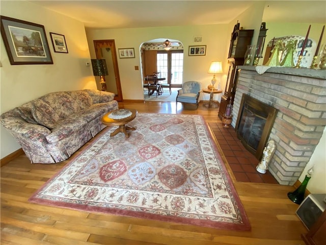 living room with arched walkways, wood finished floors, and a fireplace