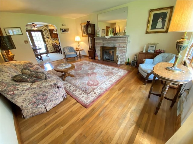 living area with arched walkways, light wood-style flooring, and a fireplace