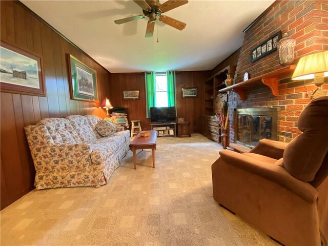 living area with carpet flooring, ceiling fan, wood walls, and a fireplace
