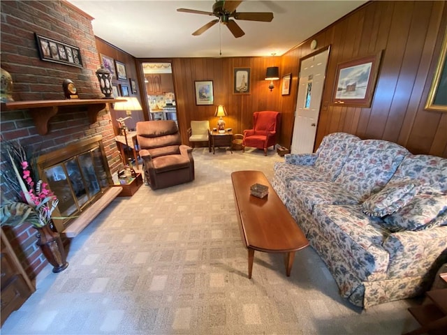 carpeted living area with ceiling fan, a brick fireplace, and wood walls