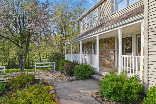entrance to property with a porch and stone siding