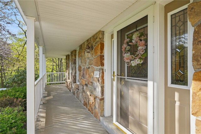 doorway to property with a porch and stone siding
