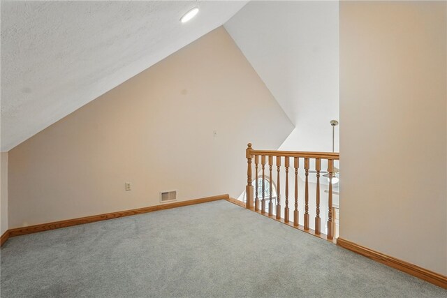 additional living space featuring carpet floors, baseboards, lofted ceiling, and visible vents