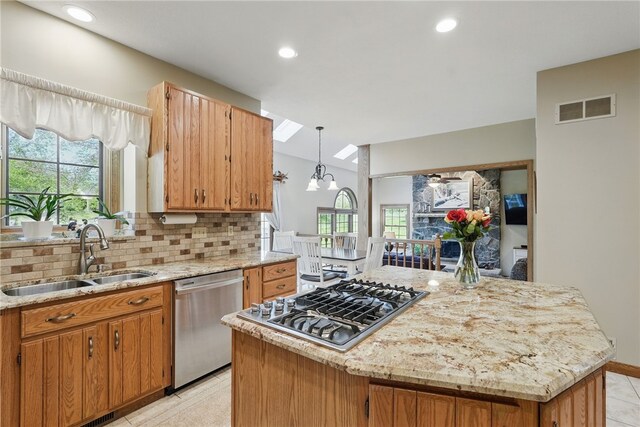 kitchen with appliances with stainless steel finishes, a sink, a center island, backsplash, and visible vents