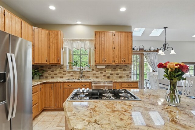 kitchen featuring a sink, appliances with stainless steel finishes, a healthy amount of sunlight, and a skylight