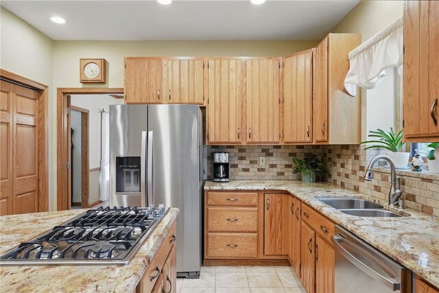 kitchen with recessed lighting, light stone counters, a sink, backsplash, and stainless steel appliances