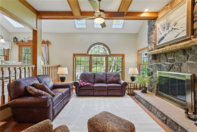living room featuring coffered ceiling, ceiling fan, beam ceiling, and a skylight