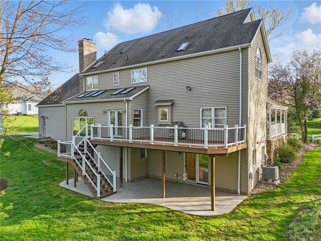 rear view of house with a chimney, a lawn, a wooden deck, a patio, and stairs