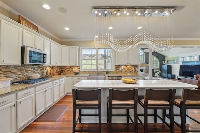 kitchen featuring a breakfast bar area, stainless steel appliances, white cabinets, and a sink