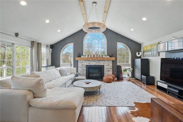 living room featuring vaulted ceiling with beams, wood finished floors, a wealth of natural light, and a fireplace