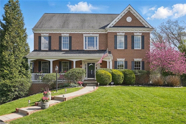 colonial inspired home featuring a porch, brick siding, and a front lawn