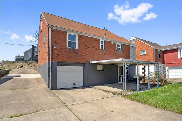 413 Pasadena Dr, Port Vue, PA 15133 - back of house featuring brick siding, a garage, central air condition unit, and concrete driveway