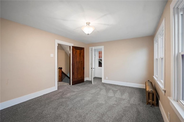 carpeted empty room with radiator and baseboards