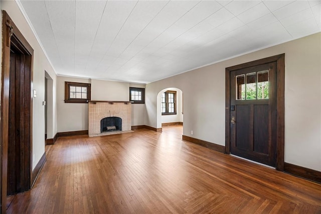 unfurnished living room with arched walkways, baseboards, a healthy amount of sunlight, and a fireplace
