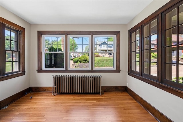 unfurnished room with light wood-type flooring, baseboards, and radiator heating unit