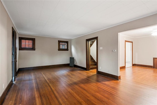 spare room with baseboards, ornamental molding, wood-type flooring, and stairs