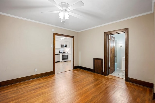 spare room with baseboards, ornamental molding, a ceiling fan, and wood finished floors