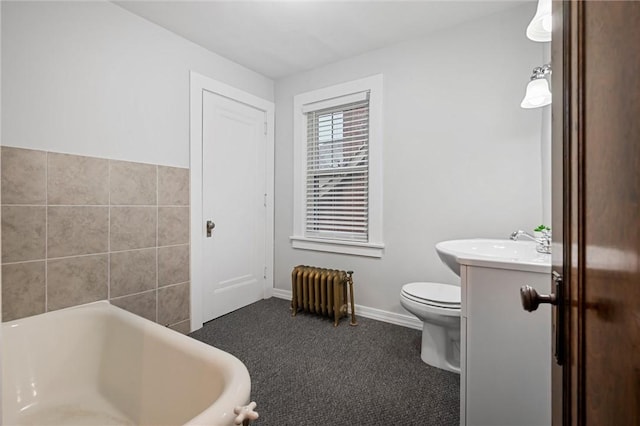 bathroom with radiator, a washtub, vanity, and toilet