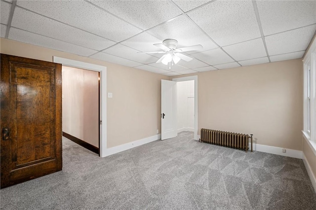 spare room featuring carpet floors, radiator, ceiling fan, and a paneled ceiling
