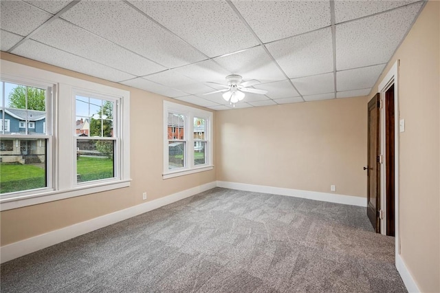 carpeted spare room with baseboards, ceiling fan, a healthy amount of sunlight, and a paneled ceiling