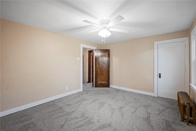carpeted empty room featuring baseboards and ceiling fan