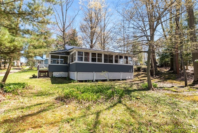 rear view of house with a lawn and a sunroom