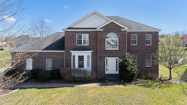 colonial inspired home with brick siding, a front lawn, and entry steps