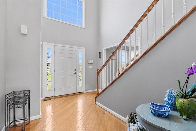 entrance foyer with baseboards, a high ceiling, wood finished floors, and stairway
