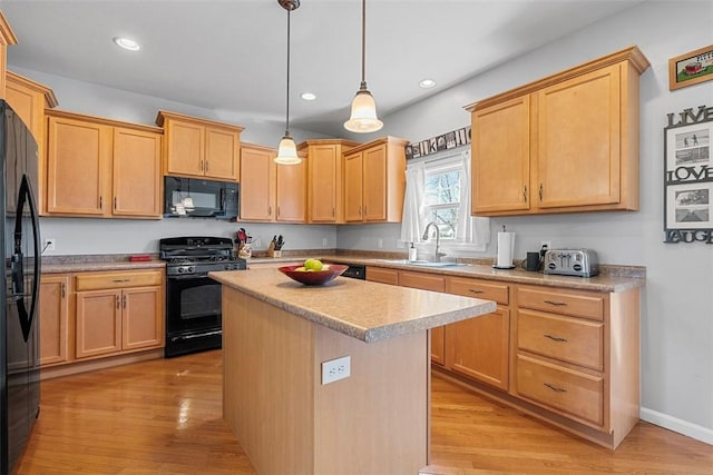 kitchen featuring a kitchen island, light wood-style floors, light countertops, a sink, and black appliances